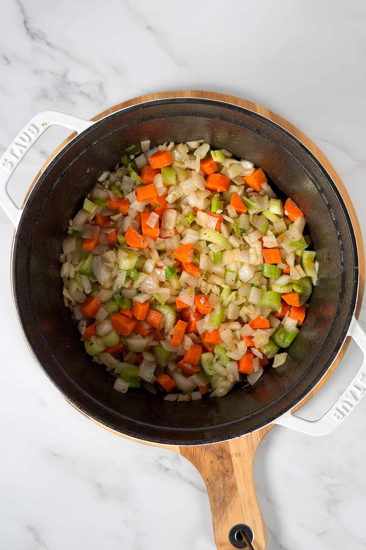 Diced onions, carrots, and celery being saut&eacute;ed in a large black pot -classic ingredients for starting a hearty burgoo.