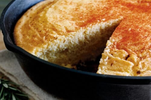Vertical view of skillet cornbread with a wedge missing