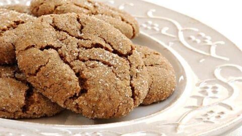 A close-up of Soft Ginger Spice Cookies, sugar-coated and stacked on an ornate white plate.