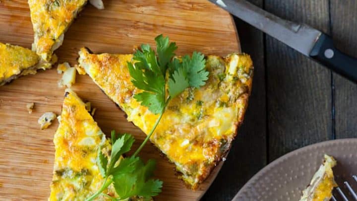 Top view of wedges of frittata on a bamboo cutting board with fresh herbs.