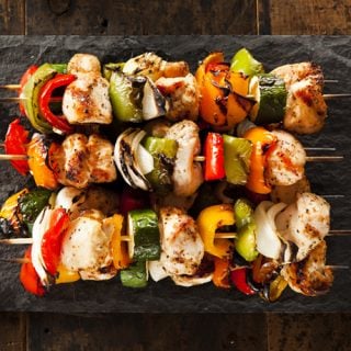 Grilled Teriyaki Chicken Kabobs on a slate serving platter on a dark wood background.