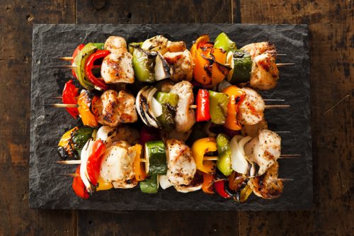 Grilled Teriyaki Chicken Kabobs on a slate serving platter on a dark wood background.