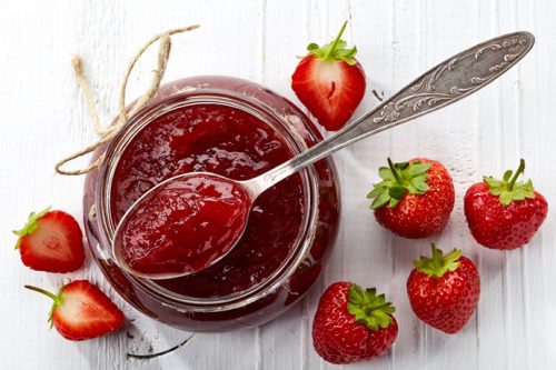 Small Batch Refrigerator Strawberry Jam with a spoon and fresh cut strawberries on a white background.