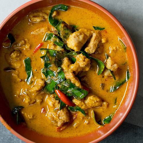 Top view of Thai Chicken Panang Curry garnished with Thai basil and Thai red peppers.