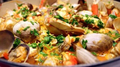 Closeup view of Seattle Style Cioppino or Fisherman's Stew in a blue bowl with fresh parsley