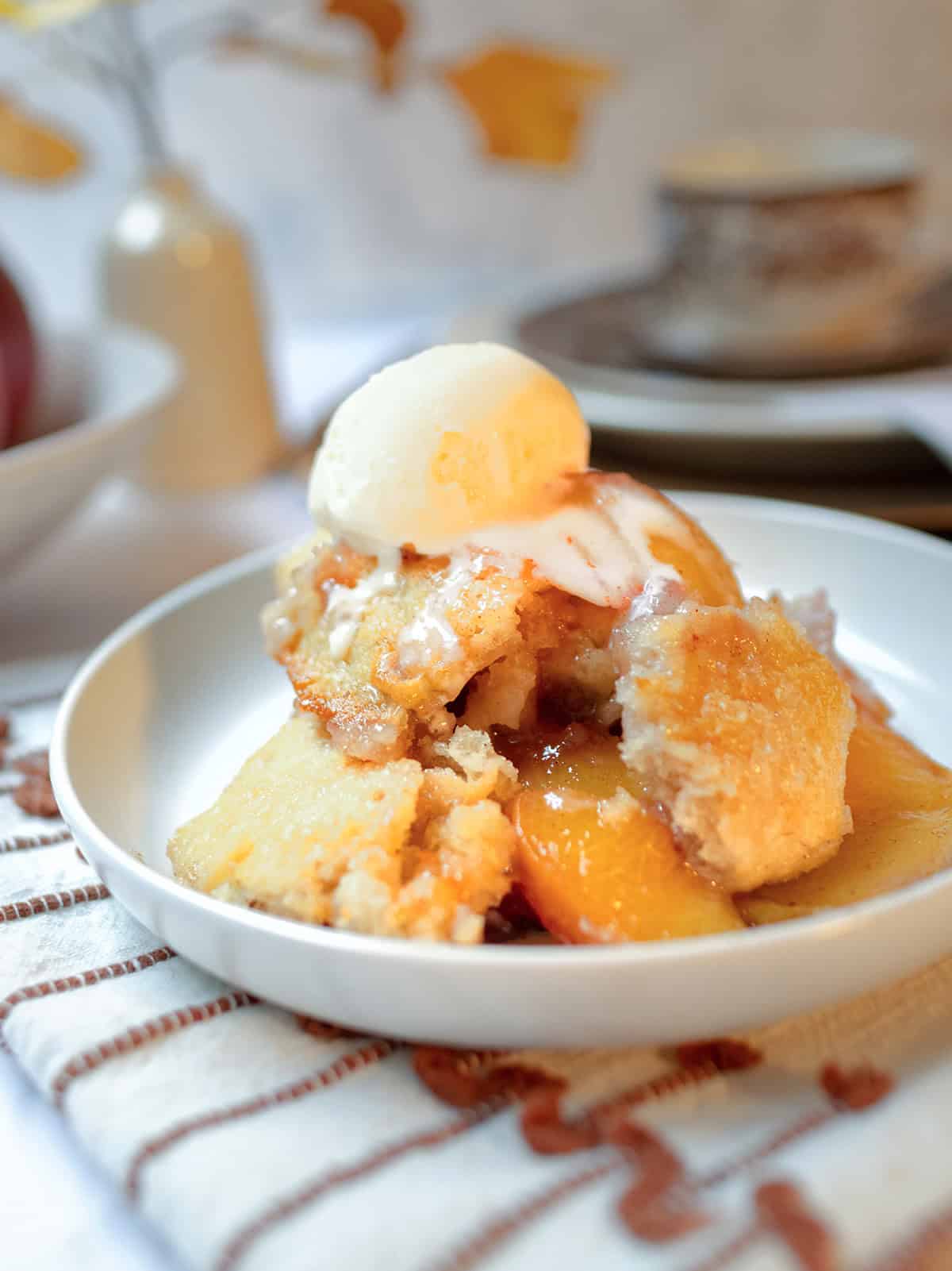Warm peach cobbler served with a scoop of vanilla ice cream.