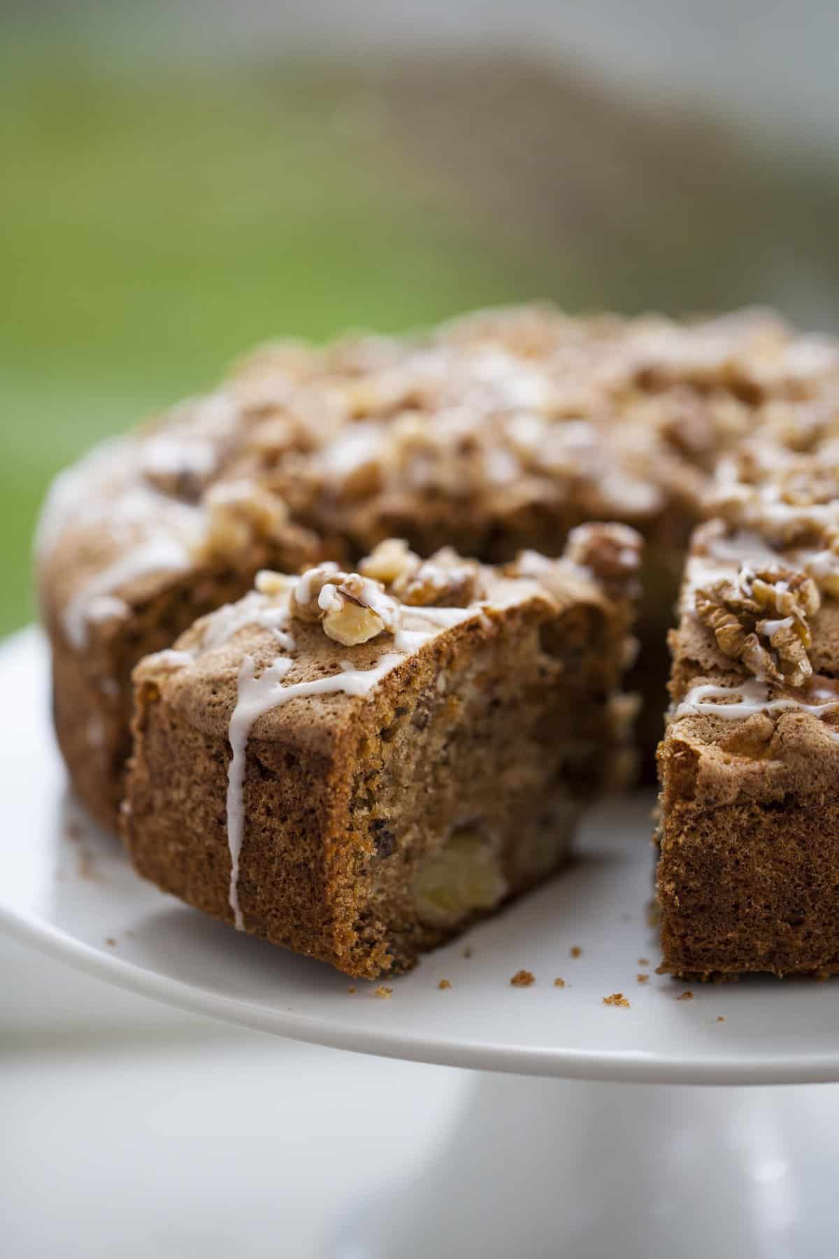 Side view of Raw Apple Cake, sliced on a white dessert stand.