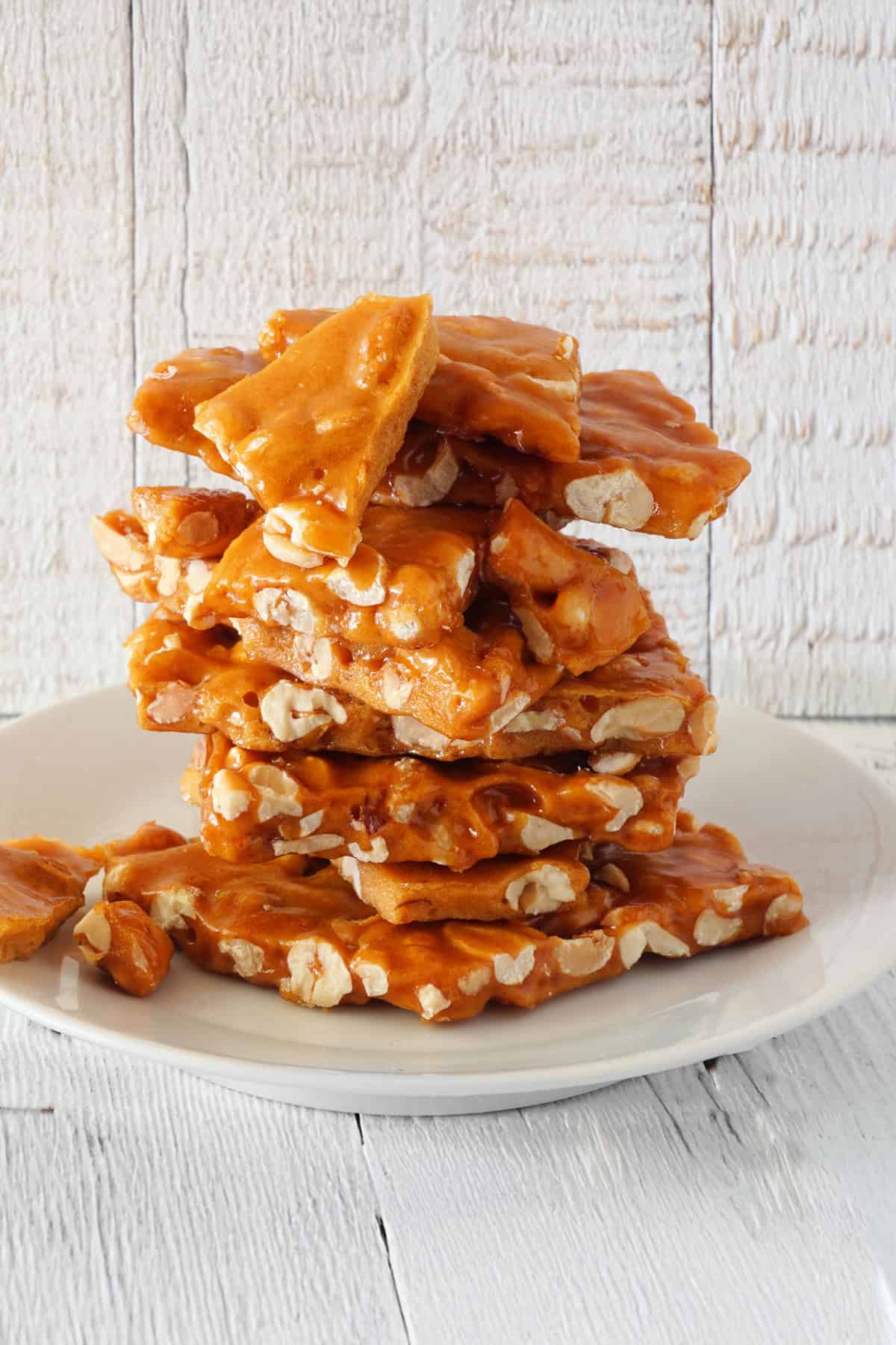 Stack of fresh peanut brittle stacked on a white plate.