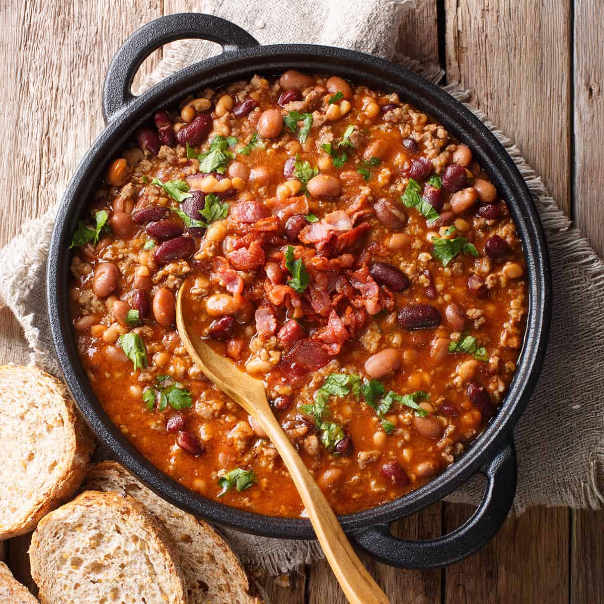 Crockpot Turkey Chili topped with fresh parsley in a large pot with whole grain bread for serving nearby.