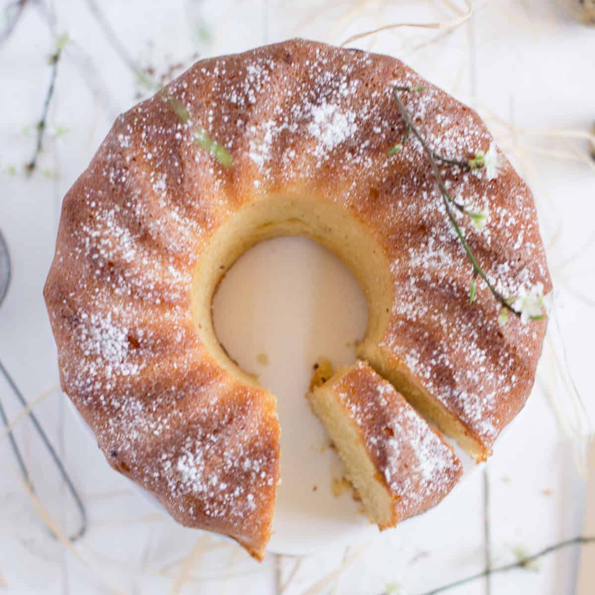 Top view of sliced citrus bundt cake on a white surface and dusted with confectioners sugar.