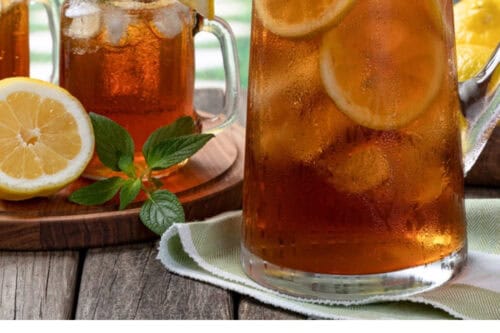 A glass pitcher and mason jars filled with sweet tea, lemon slices, and mint sit on a wooden surface, with a sliced lemon nearby. Text below reads: "Best Tea for Southern Sweet Tea.