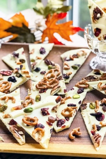 Square image of triangle portions of white chocolate park with pistachios, pretzels, and dried fruit.