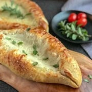 A delightful cheese boat is beautifully displayed on a wooden board, making it an irresistible centerpiece.