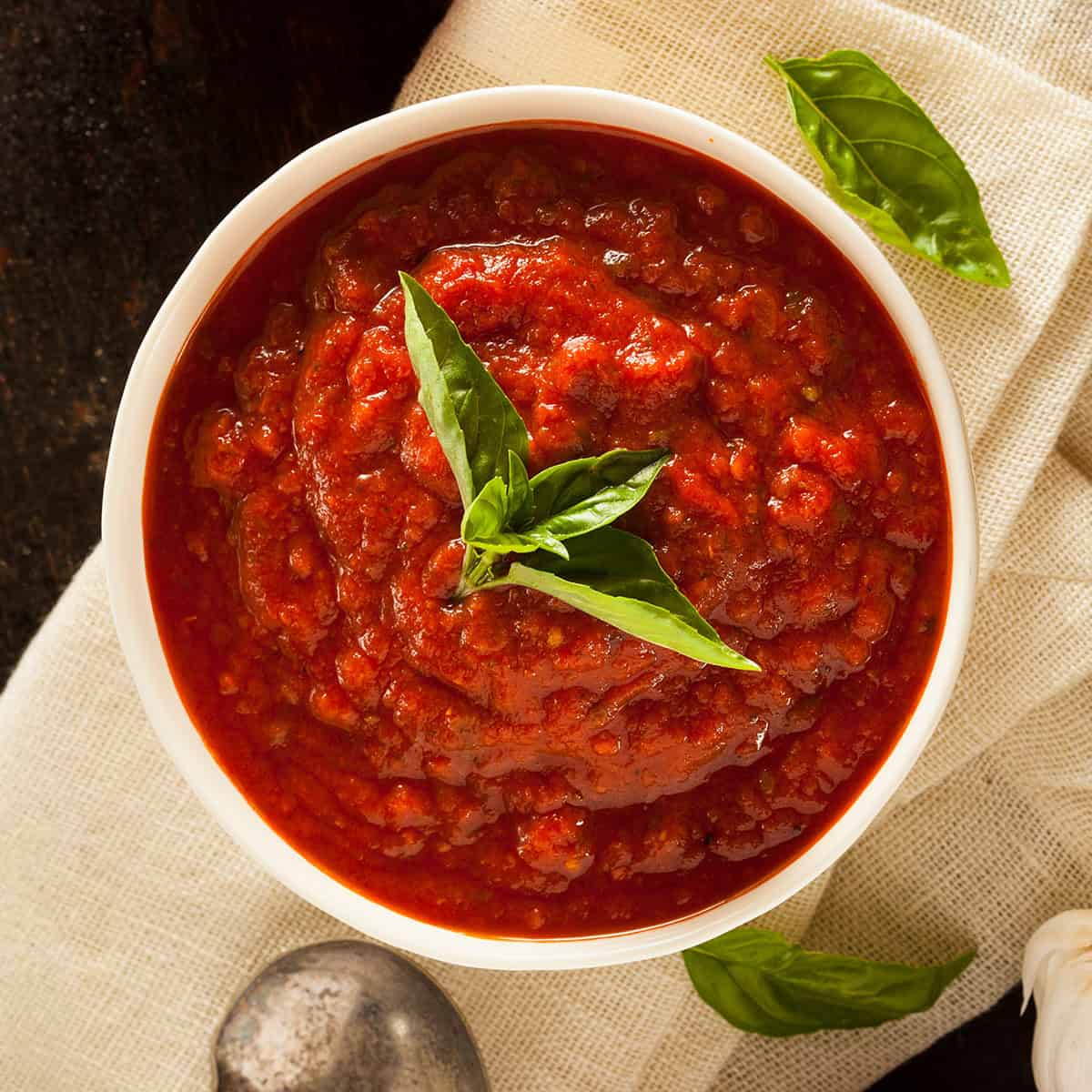 Top view of Marcella Hazan's 3 ingredient tomato sauce with sprigs of fresh basil.