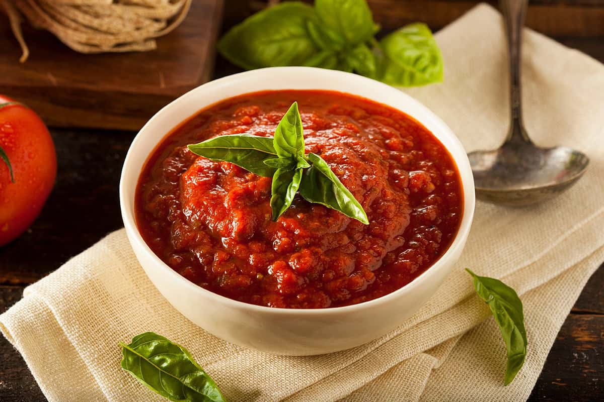 Bowl filled with Marcella Hazan's famous pasta sauce topped with a basil sprig.