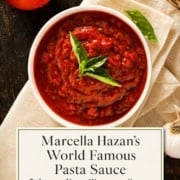 Single image poster of Marcella Hazan's 3-ingredient tomato pasta sauce in a rustic bowl, rich red sauce over fresh pasta, styled with warm natural light and earthy tones.