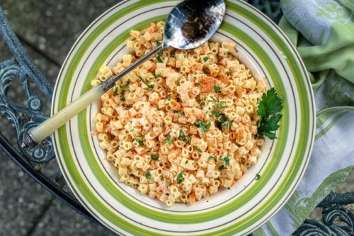 pasta salad with shredded carrots in a blue and white bowl