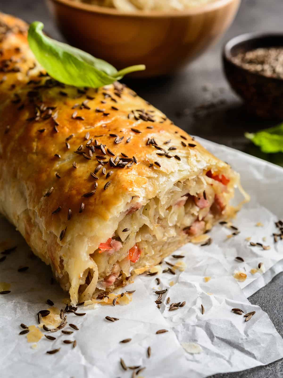 Unsliced Krautstrudel with a golden phyllo dough and topped with caraway seeds.