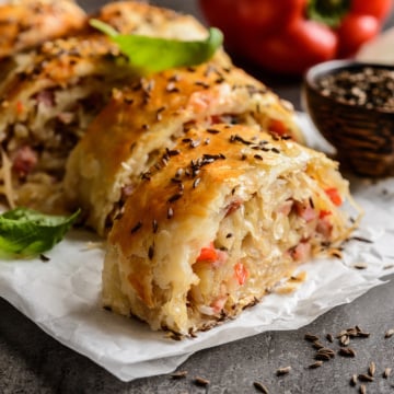 Closeup slice of Krautstrudel with herbs and caraway seeds on top.