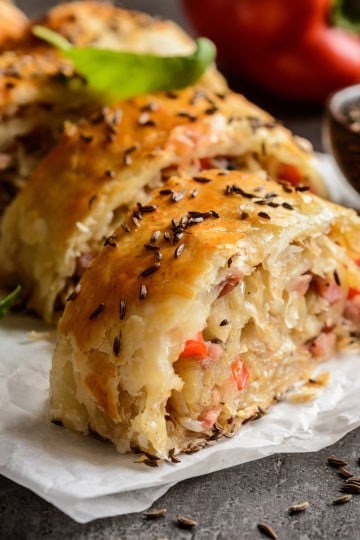 Closeup slice of Krautstrudel with herbs and caraway seeds on top.