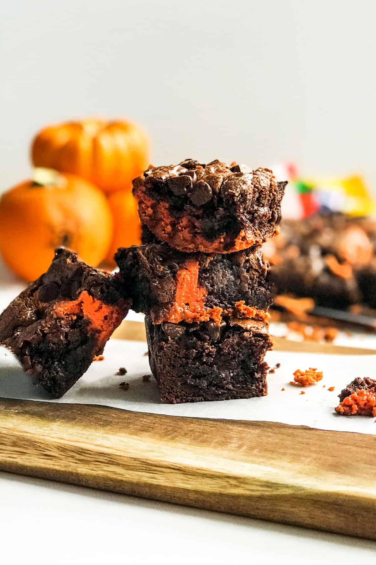 Stack of peanut butter chocolate swirled brownies on a parchment lined wooden serving board.