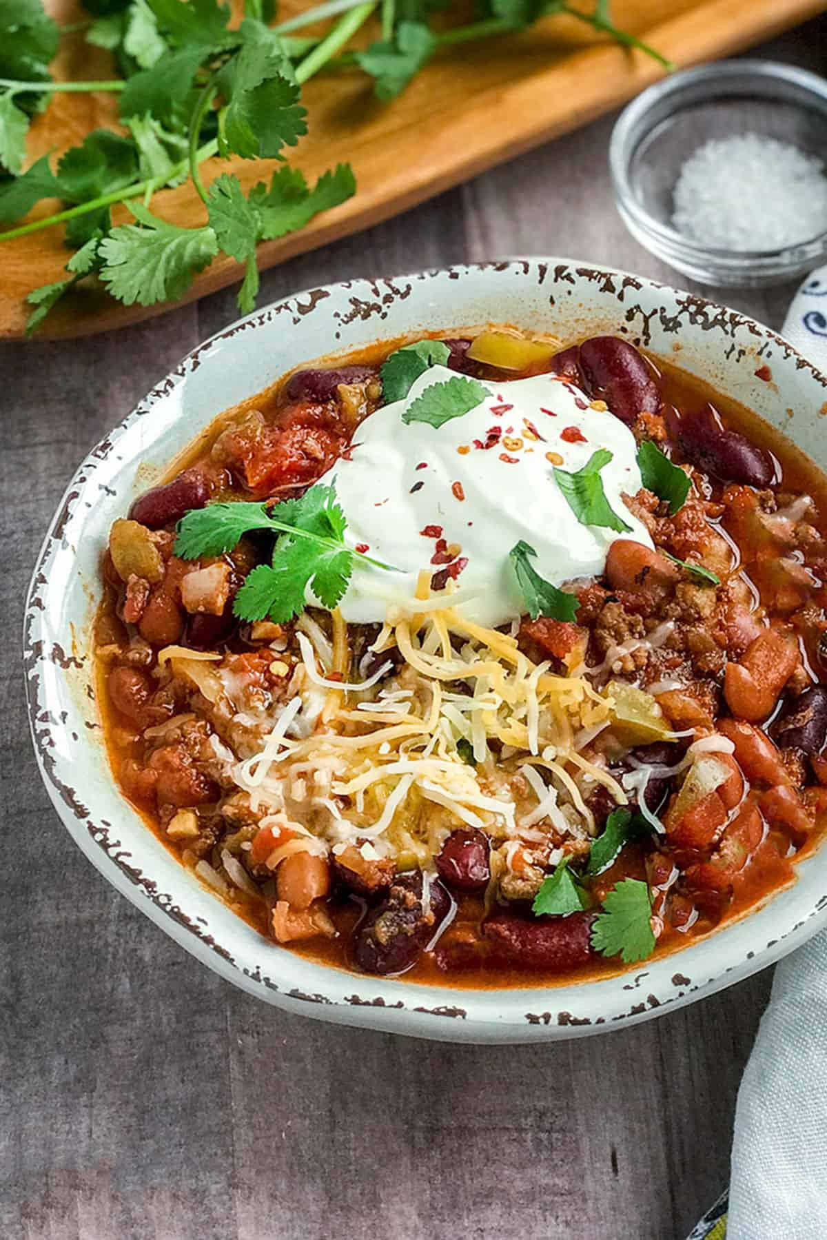 Bowl of thick and hearty Instant Pot chili topped with sour cream and cilantro - quick recipe with tips for thickening chili naturally