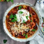 Bowl of Instant Pot chili topped with sour cream, shredded cheese and fresh cilantro.