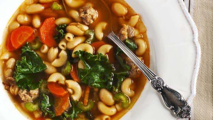 Close up of a white bowl of Instant Pot Turkey, Vegetable and Pasta Soup with a vintage spoon.
