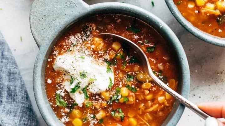 Top view of a bowl of Greek Chicken and Rice with fresh herbs, tomatoes, and cucumbers