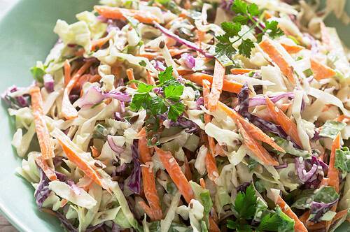 Coleslaw with fresh parsley and carrots in a bowl.