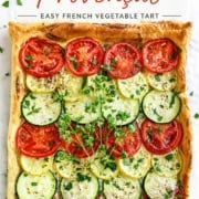 Square vegetable tart with sliced tomatoes, zucchini, and yellow squash arranged in rows on puff pastry, garnished with herbs. This Tian Provençal showcases the vibrant flavors of classic French vegetables in an easy-to-make tart. Text reads "Tian Provençal: Easy French Vegetable Tart.