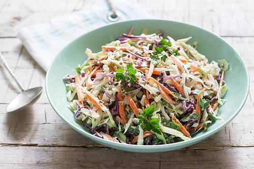 Closeup horizontal view of homemade coleslaw in a light blue bowl.
