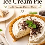 A delicious Ice Cream Pie with a graham cracker crust is sliced and served on a white plate, topped with whipped cream, chocolate shavings, and a mint garnish. In the background, a slice of this creamy dessert sits ready on a smaller plate.