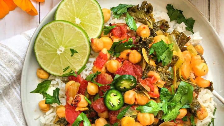 Top view of chickpea curry on white plate with sliced limes.