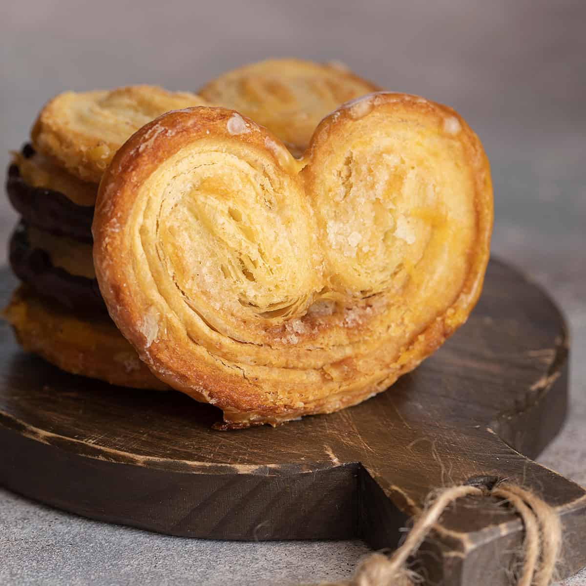 Square image of Palmier on dark wooden serving board with more stacked behind.