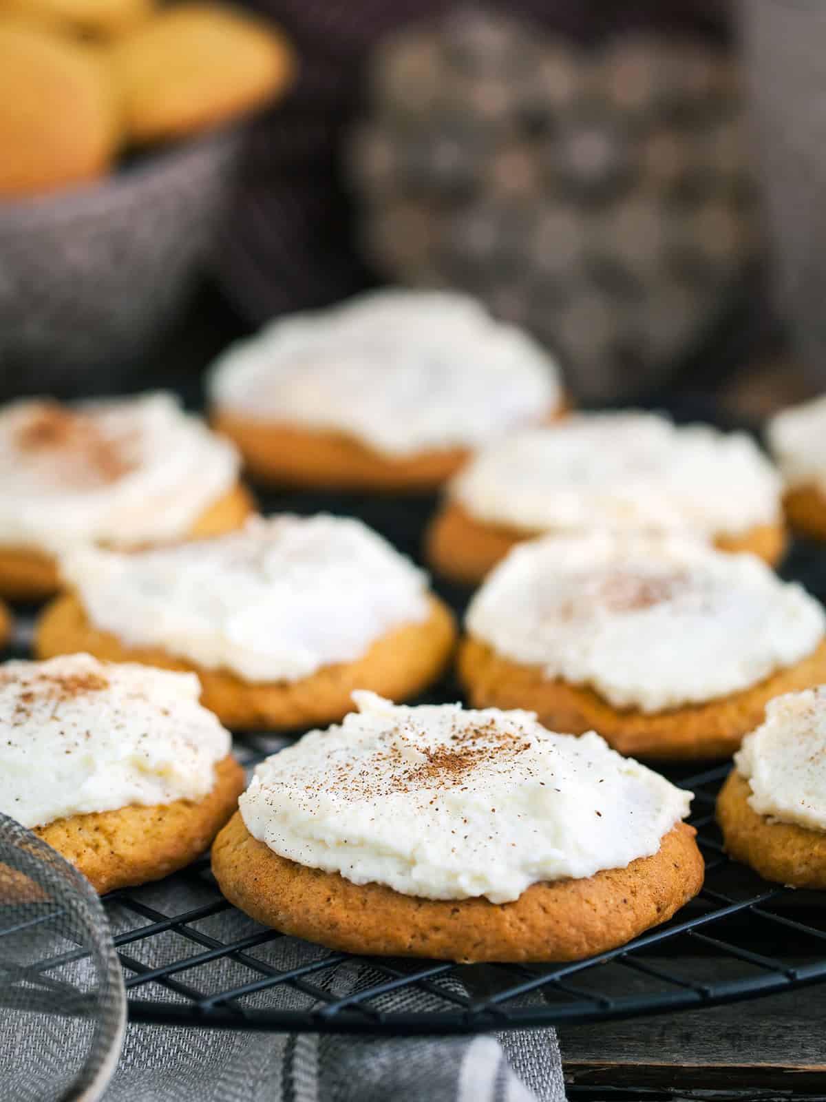 Frosted pumpkin spice cookies with vanilla butter frosting on a cooling rack.