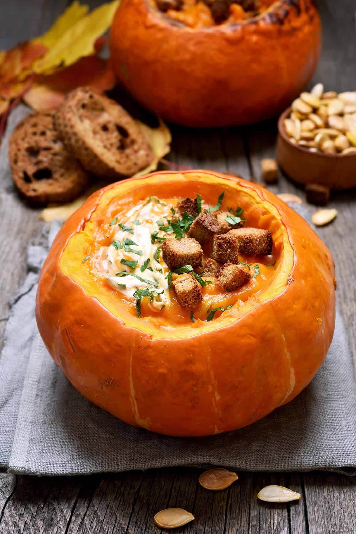 Pumpkin Curry Soup served in hollowed out pumpkins, topped with croutons, and cream.