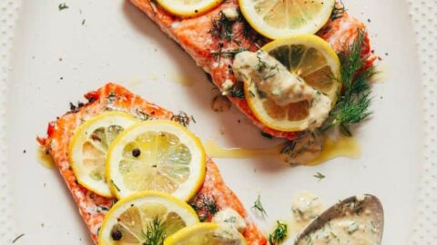 Top view of cooked salmon portions with slices of lemon on top.