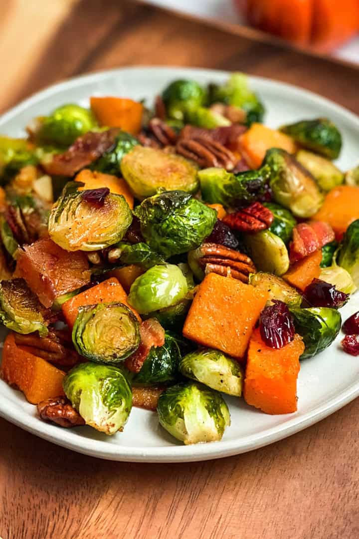 Square image of roasted Brussels Sprouts, butternut squash, and root vegetables on a serving platter.