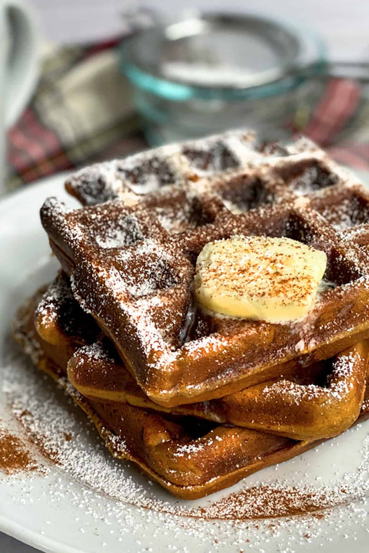 Side view of stacked gingerbread waffles with butter melting down the sides.