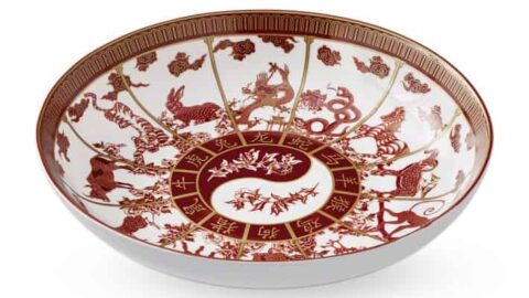 A round ceramic bowl featuring red and white Chinese zodiac and animal motifs inspired by Lunar Chinese New Year, with intricate floral patterns in the center.