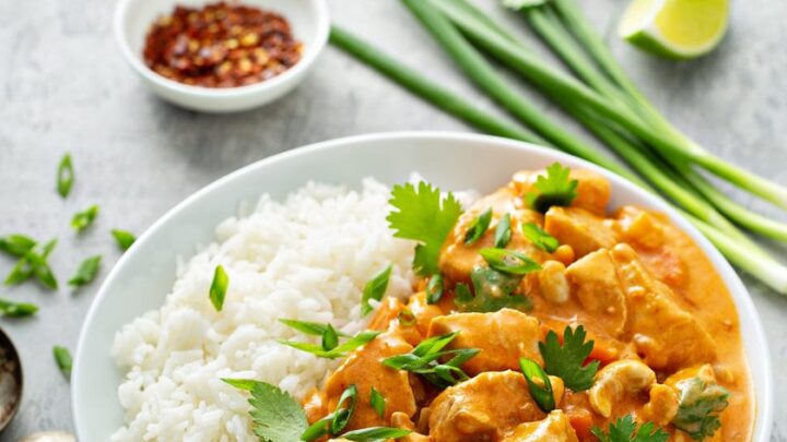Top view of Chicken Curry with rice, cilantro, limes, and green onions