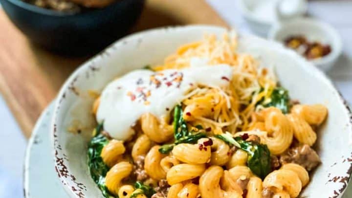 Side view of a bowl of Instant Pot Taco Mac and Cheese with fixings in the background.