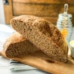 Halved no-knead whole wheat bread shows a perfect crumb with honey in the background for serving.