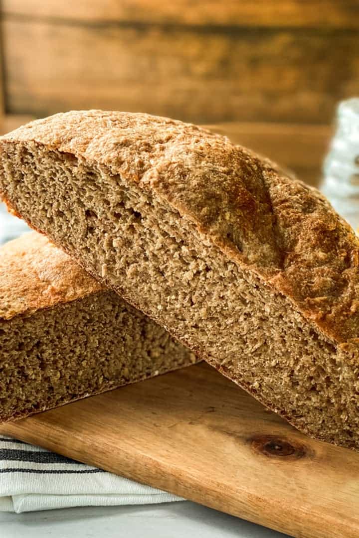 Halved no-knead whole wheat bread shows a perfect crumb with honey in the background for serving.