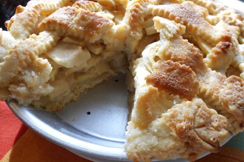A homemade apple pie with a lattice crust sits in a metal pie pan, with one slice removed to reveal the apple filling-a classic choice for Father's Day dessert recipes.