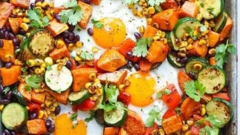 This delicious sheet pan breakfast features baked eggs, sweet potatoes, zucchini, black beans, corn, red bell peppers, and fresh cilantro—all seasoned and roasted together for a colorful morning meal.