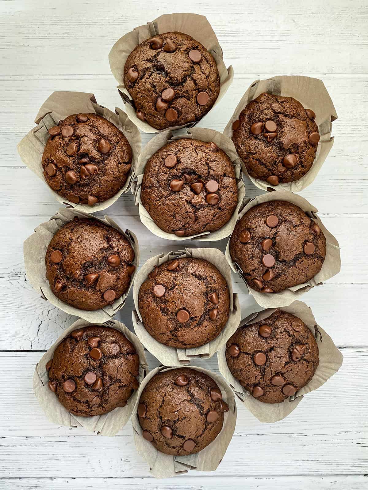 Top view of Double Chocolate Zucchini Muffins on wooden serving surface.