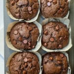 Chocolate Zucchini Muffins in paper sleeves cooling in a muffin tin.