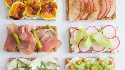 Nine rectangular crispbreads are topped with various ingredients including fruit, vegetables, cheese, smoked salmon, ham, and herbs—perfect for Healthy Lunch Ideas—arranged in three rows on a white background.